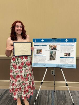 student showing poster and award